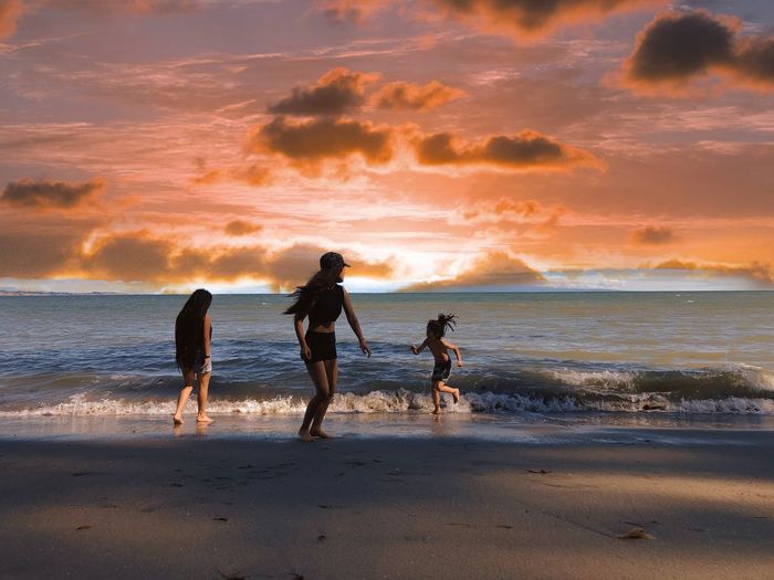 People on beach against sky during sunset