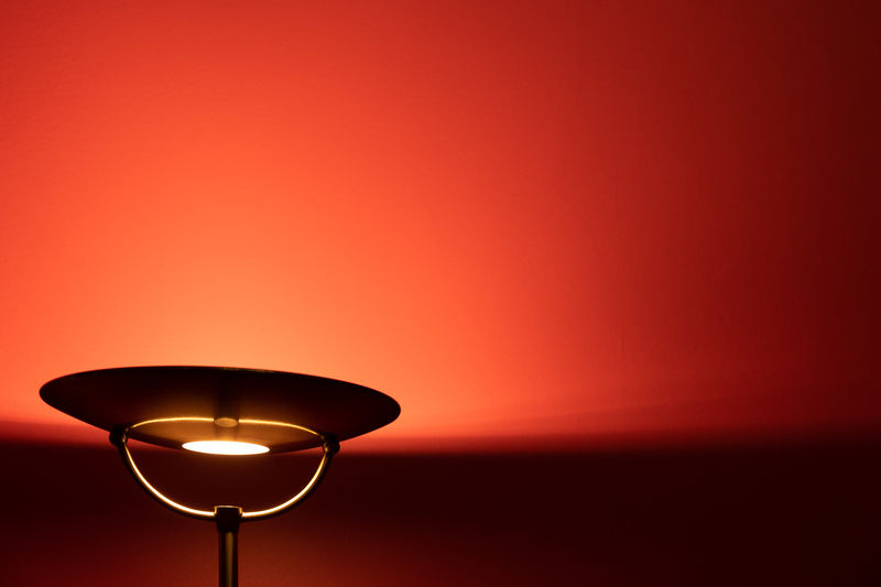 Metal floor lamp lighting red wall with copy space
