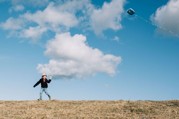 Young boy flying a kite on the top of a hill on a beautiful day