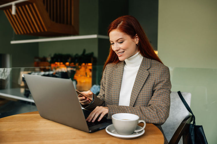 Young woman using laptop while sitting on table