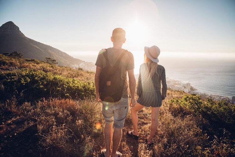 Rear view of friends standing on mountain against sky