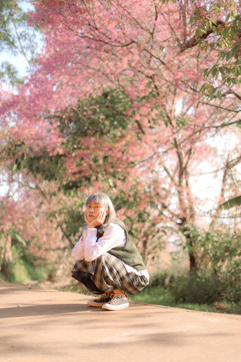 Portrait of woman standing by cherry tree in park