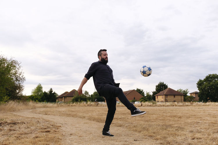 Mature man playing with soccer ball in field