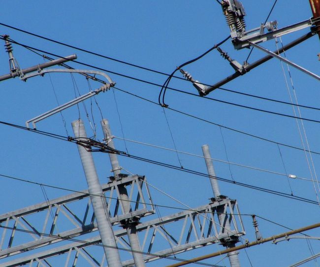 Low angle view of electricity pylon against blue sky