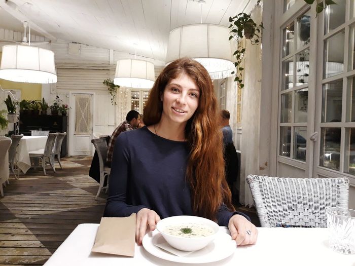 Portrait of smiling young woman sitting in restaurant