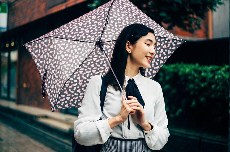 Woman holding umbrella while standing on rainy day