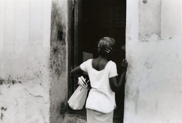 Rear view of a woman standing against the wall