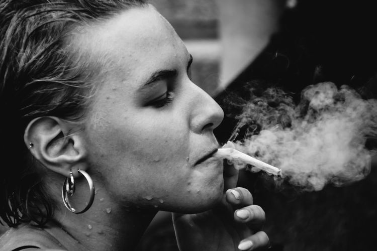 Close-up portrait of woman smoking cigarette