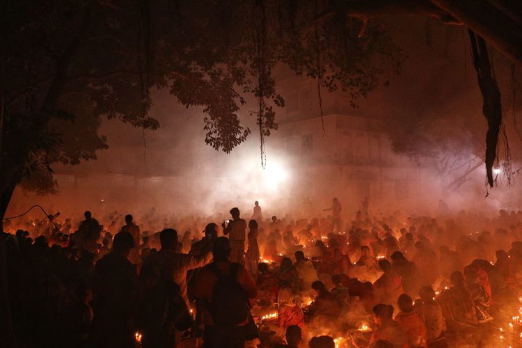 People are praying at rakher upobash under big tree in a smokey environment
