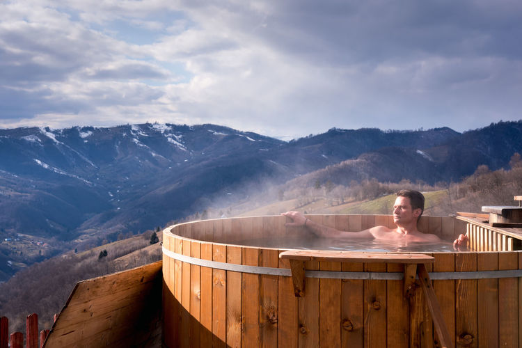 Adult man relaxes in barrel with hot water, in nature, transylva