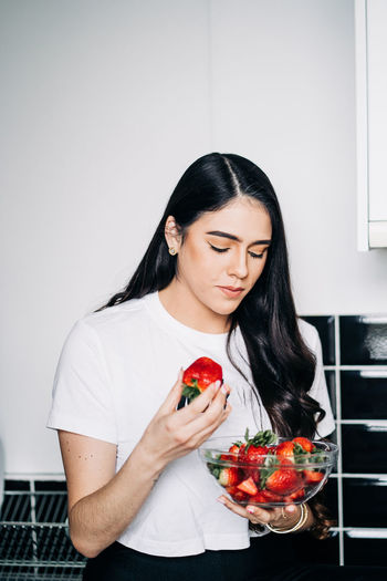 Young woman holding bowl of strawberries