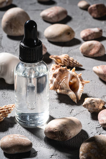Skin care essence oil dropper in glass bottle near to seashells and pebbles