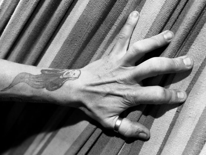 Cropped hand of person with tattoo on bed