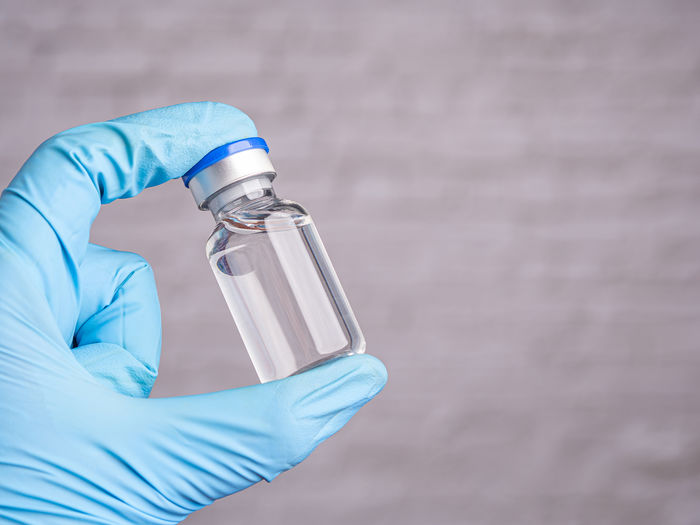 Midsection of scientist holding bottle