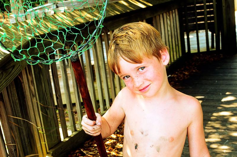 Boy holding butterfly net on boardwalk