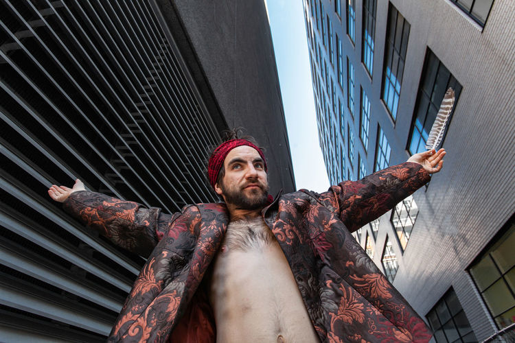 Low angle view of shirtless man standing amidst buildings