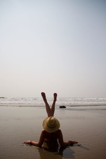 Rear view of woman relaxing on shore against clear sky