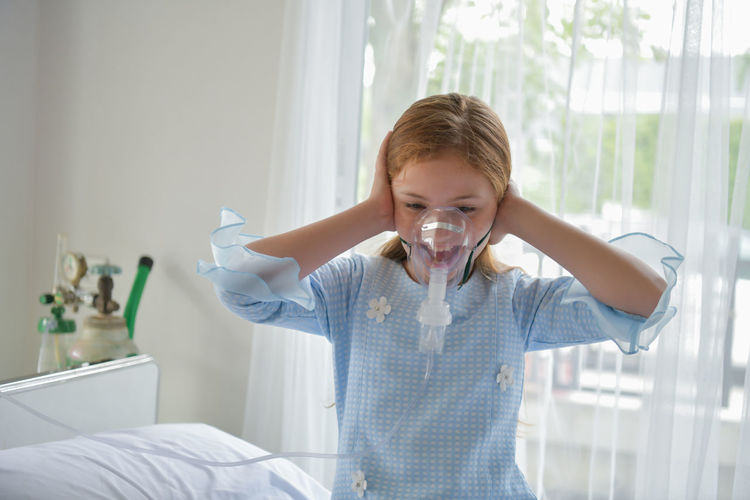 Girl with oxygen mask on bed at hospital