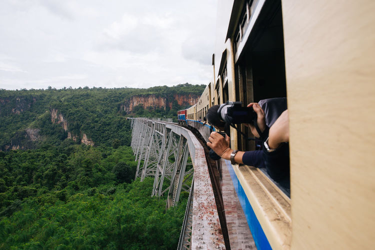 Cropped image of person photographing mountains from train