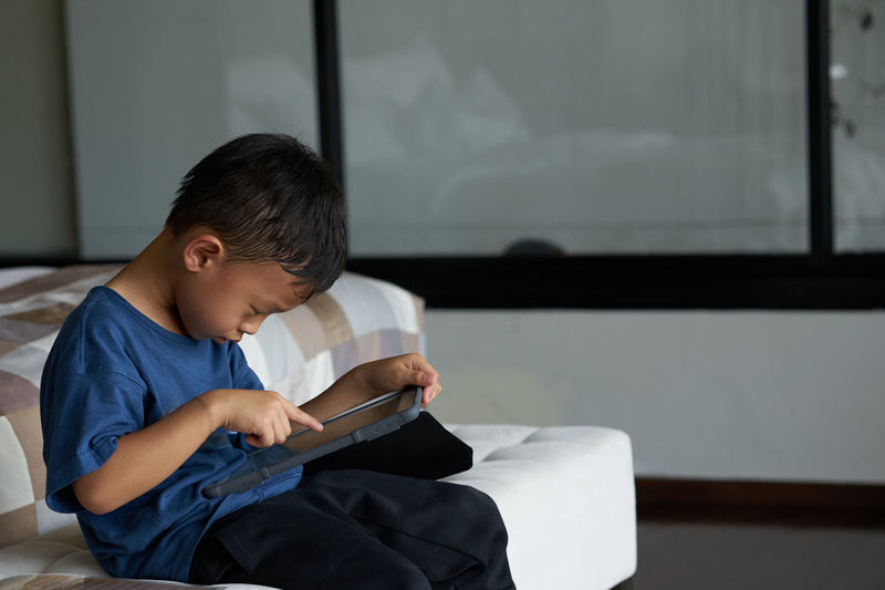 Cute boy using digital tablet at home