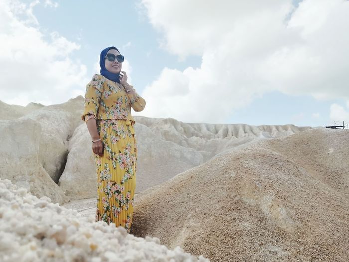 Woman standing on land at desert against sky