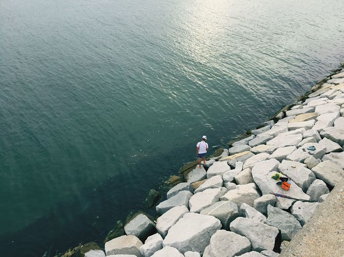 High angle view of man standing on rocks by sea