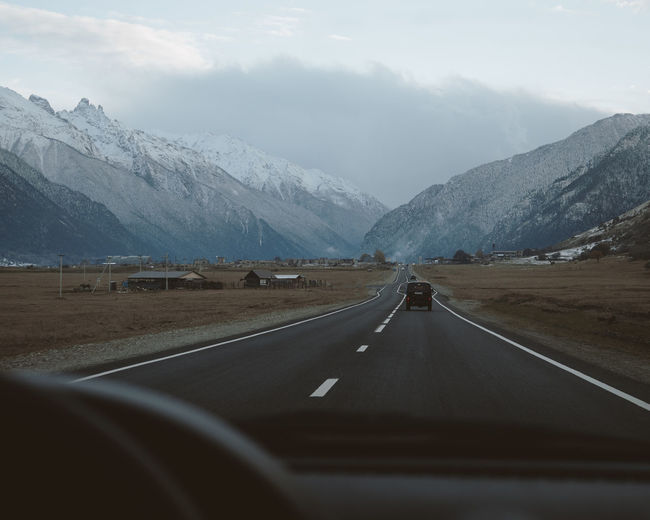 Road amidst mountains seen through car windshield