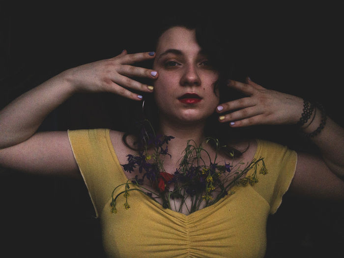 Portrait of young woman with flowers against black background