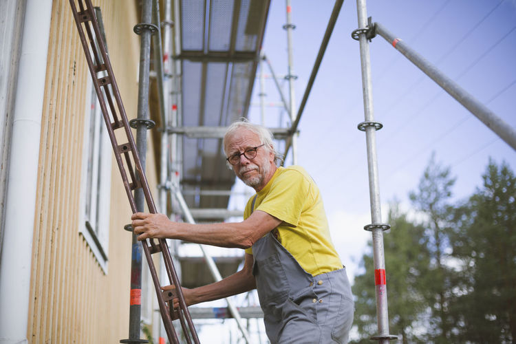 Senior man standing on ladder