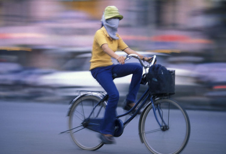 Blurred motion of woman riding bicycle on road