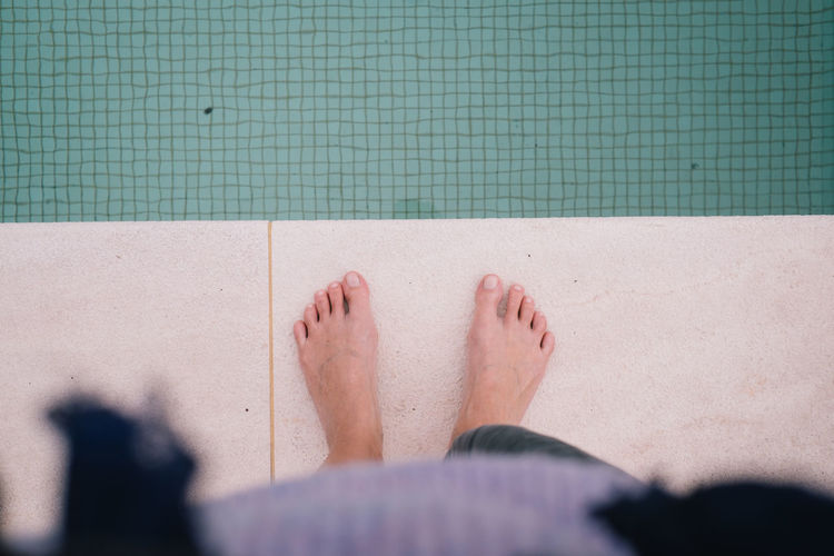 Low section of woman standing by swimming pool