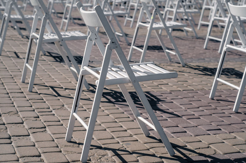 White folding chairs are placed on the square on pavement. quarantine restrictions, mass events