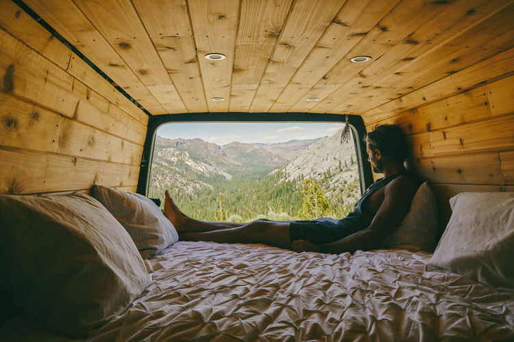 Young man sitting on bed of camper van observing the views of yosemite