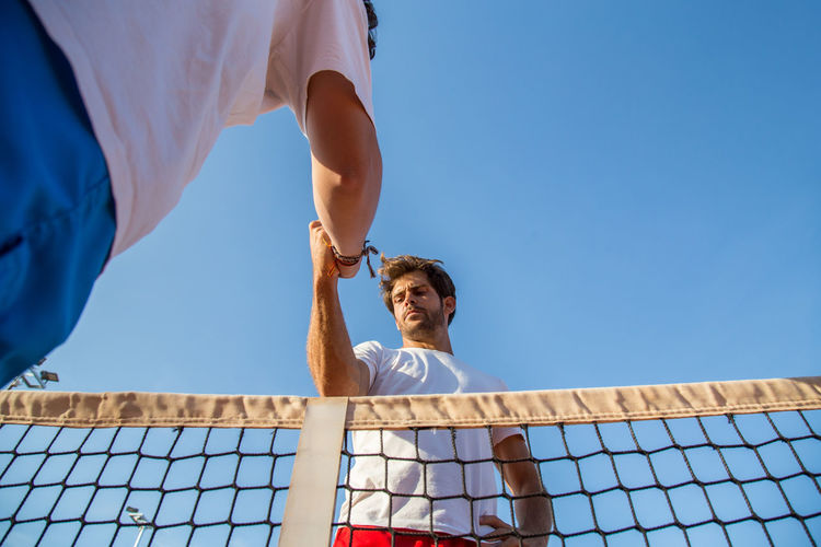 Low angle view of young man playing against clear blue sky