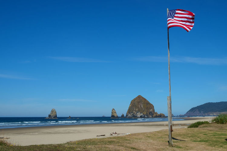 American flag on beach against blue sky