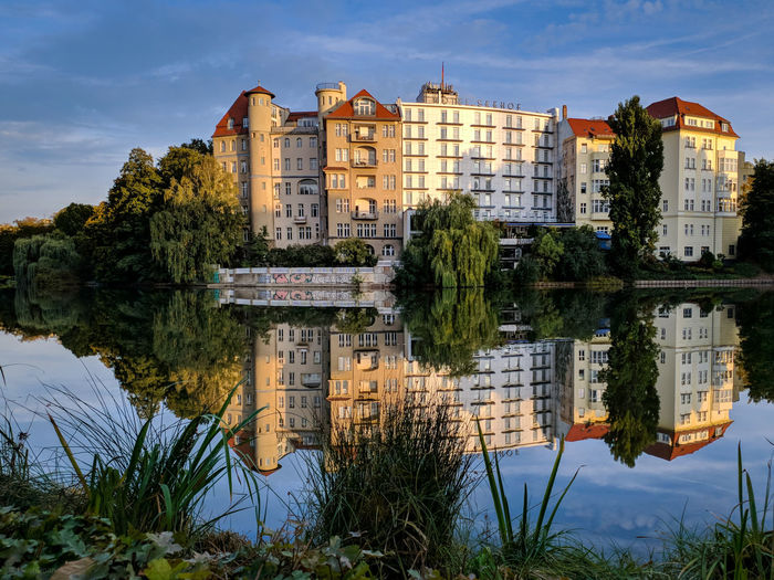Buildings by lake against sky in city