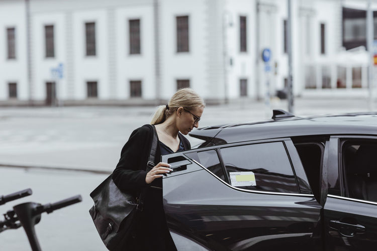 Businesswoman with bag sitting in car