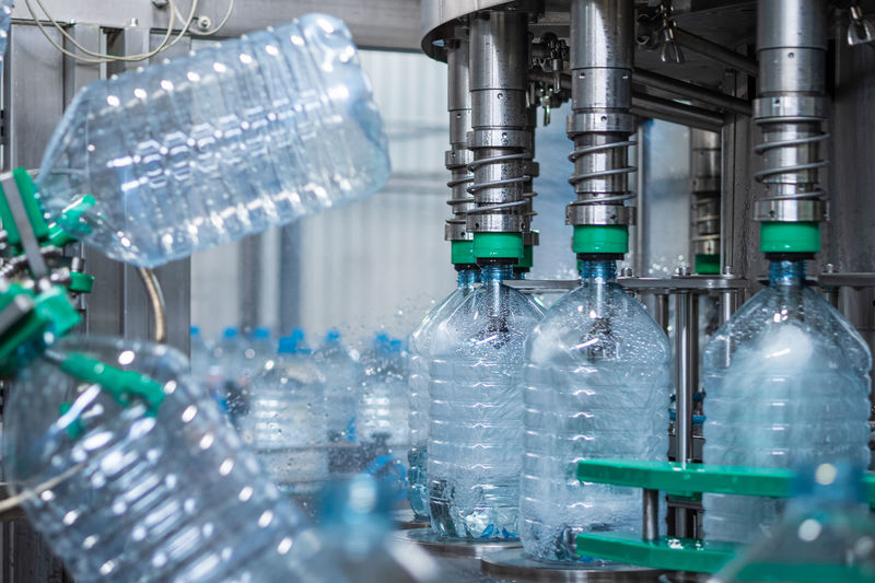 Five-liter plastic bottles are filled with water in a filling machine