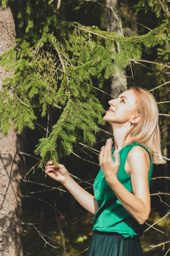 Smiling woman standing by tree against plants