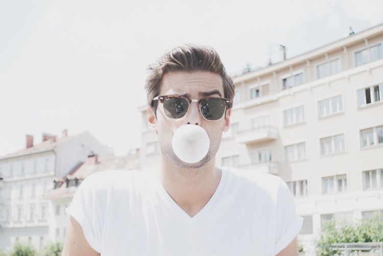 Portrait of a young man blowing bubble gum outdoors