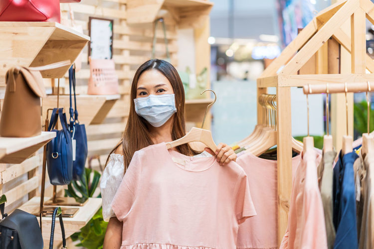Portrait of woman wearing mask standing at store