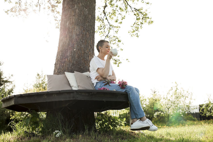 side view of woman sitting on tree