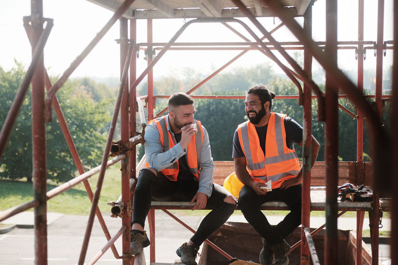 Smiling workers talking while sitting on built structure