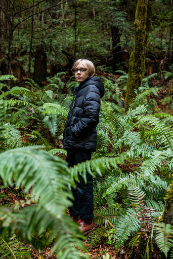 Teenage boy standing in fern grove in northern california forest
