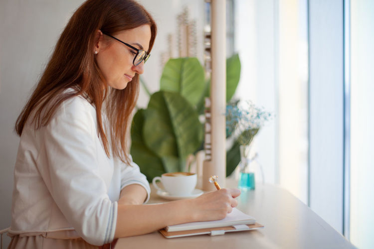 Young woman using phone while sitting on table