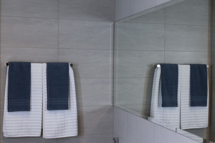 White and blue colour towels on rack in bathroom.