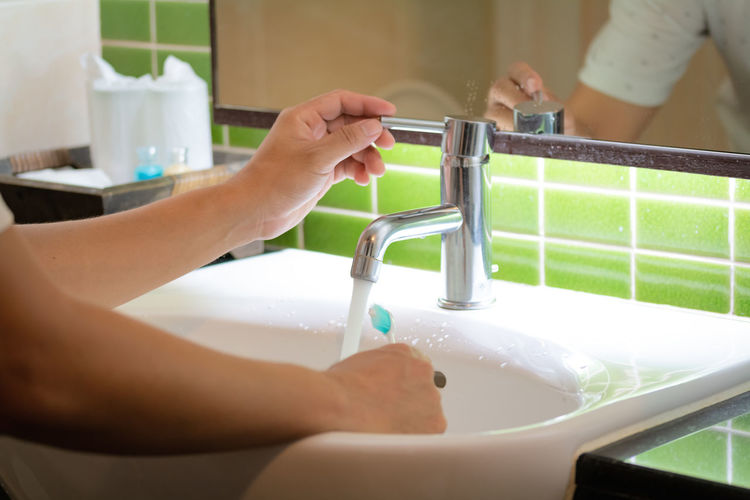 Cropped image of woman washing hands in bathroom sink at home