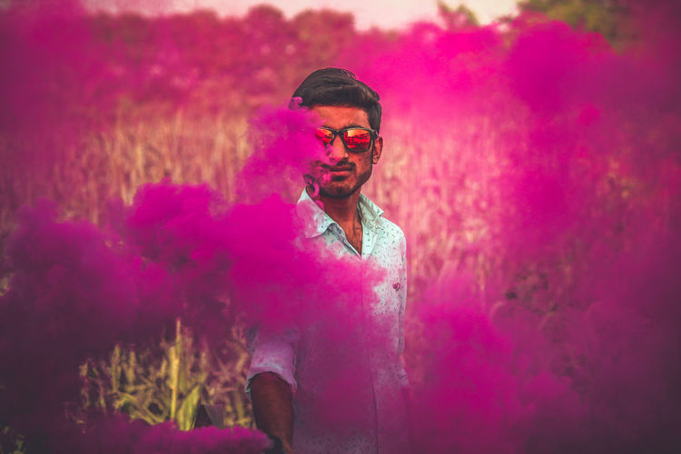 Portrait of young man holding smoke bomb