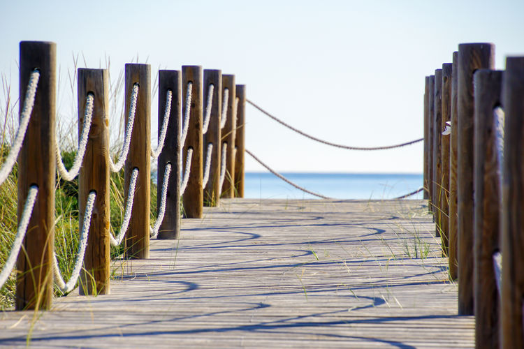 Close-up of wooden walkway on beach against clear sky
