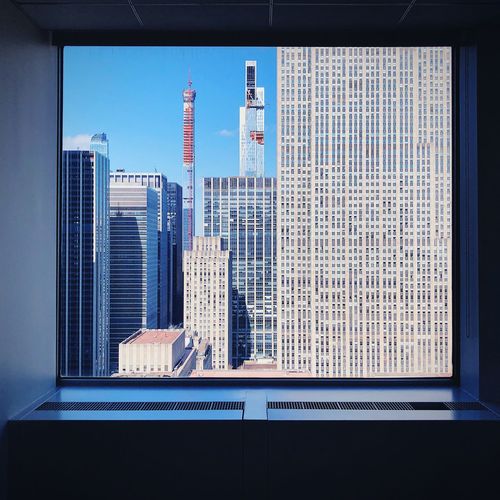 Modern buildings against sky seen through glass window